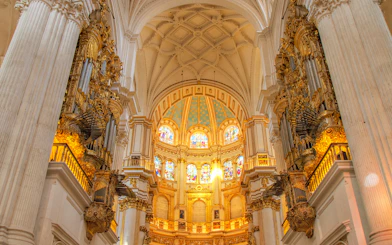 Interior view of Cathedral and Royal Chapel of Granada with ornate columns and stained glass windows.