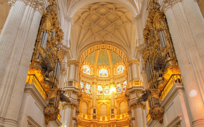 Interior view of Cathedral and Royal Chapel of Granada with ornate columns and stained glass windows.