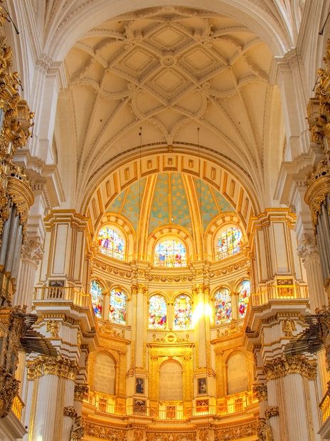 Interior view of Cathedral and Royal Chapel of Granada with ornate columns and stained glass windows.