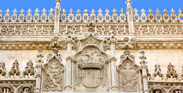 Ornate stone facade of the Cathedral and Royal Chapel of Granada, featuring intricate Gothic carvings.