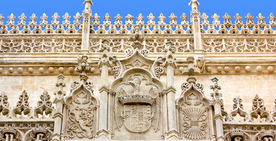 Ornate stone facade of the Cathedral and Royal Chapel of Granada, featuring intricate Gothic carvings.