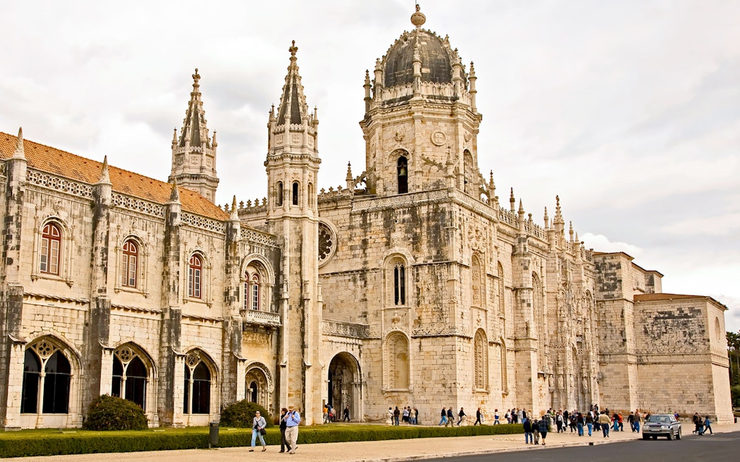 Jerónimos Monastery facade in Lisbon with visitors exploring the historic site.