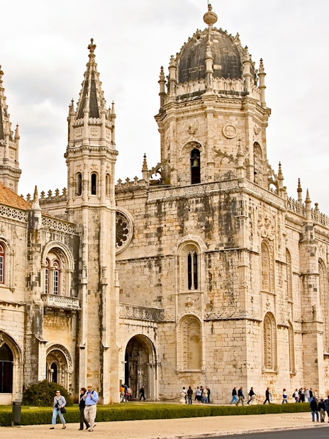 Jerónimos Monastery facade in Lisbon with visitors exploring the historic site.