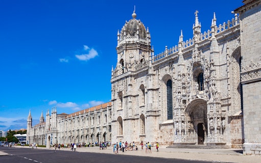 Jerónimos Monastery facade in Lisbon with tourists outside.