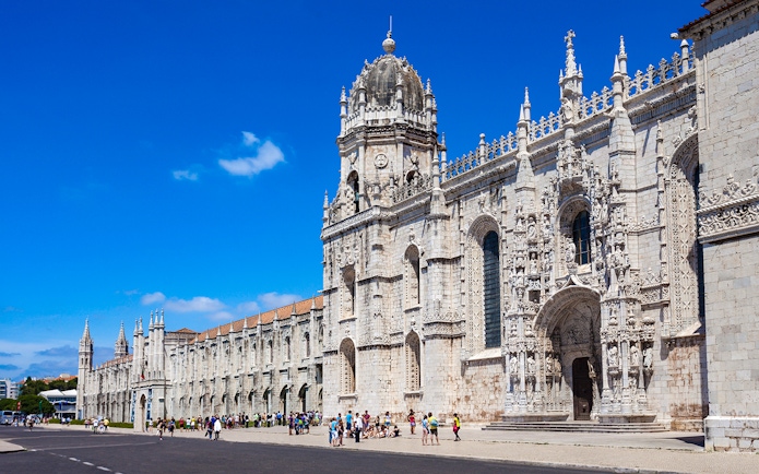 Jerónimos Monastery facade in Lisbon with tourists outside.