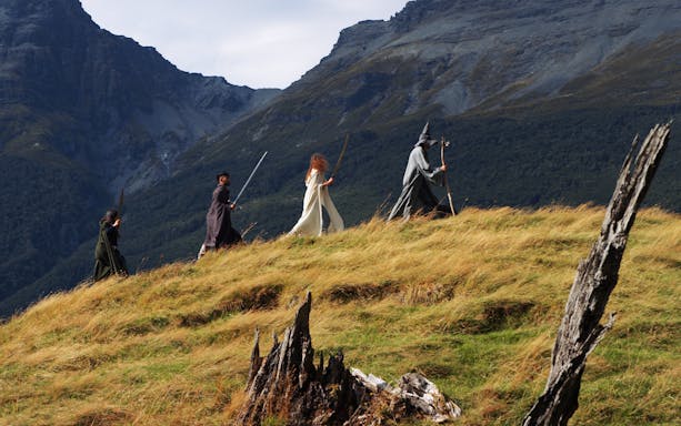 Guided tour group in costume walking through scenic mountain landscape near Queenstown.
