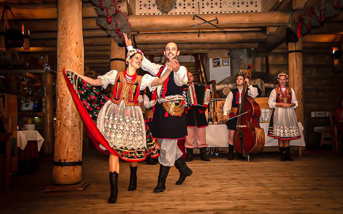 Polish folk dancers performing with musicians during an all-you-can-eat dinner show.