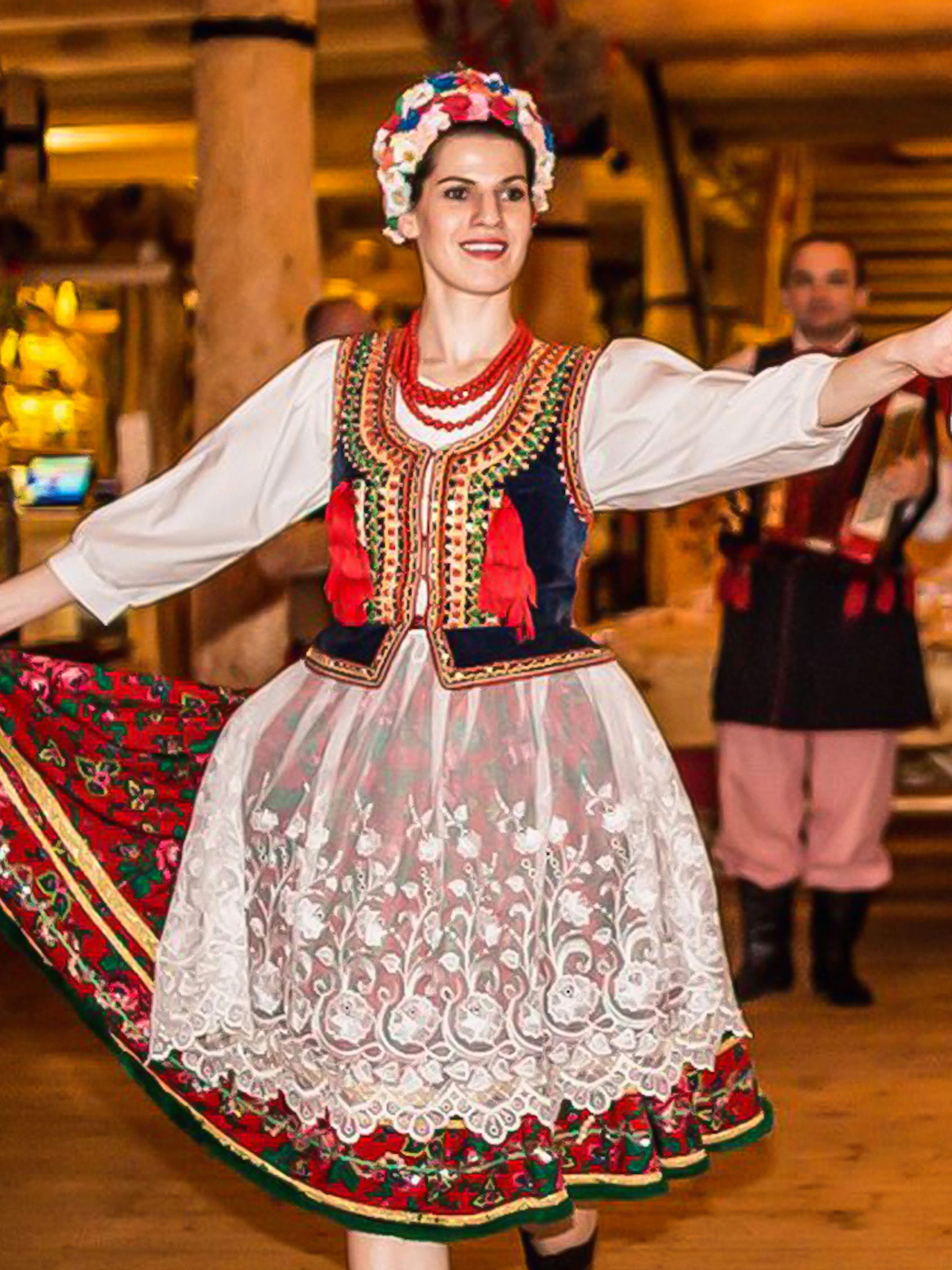 Dancers in traditional Polish costumes performing at a folk show with dinner.