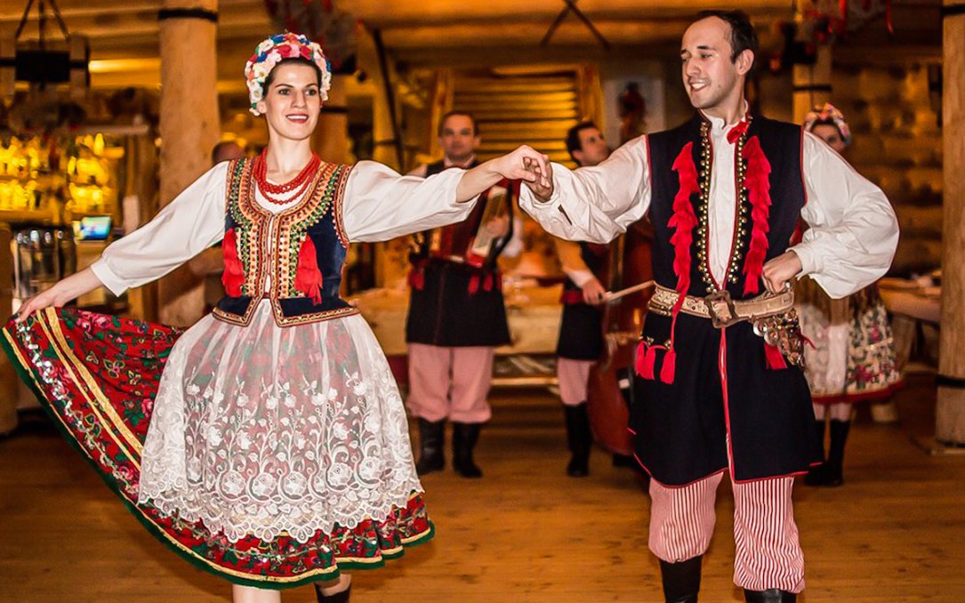 Dancers in traditional Polish costumes performing at a folk show with dinner.