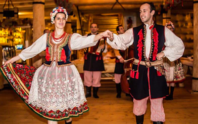 Dancers in traditional Polish costumes performing at a folk show with dinner.