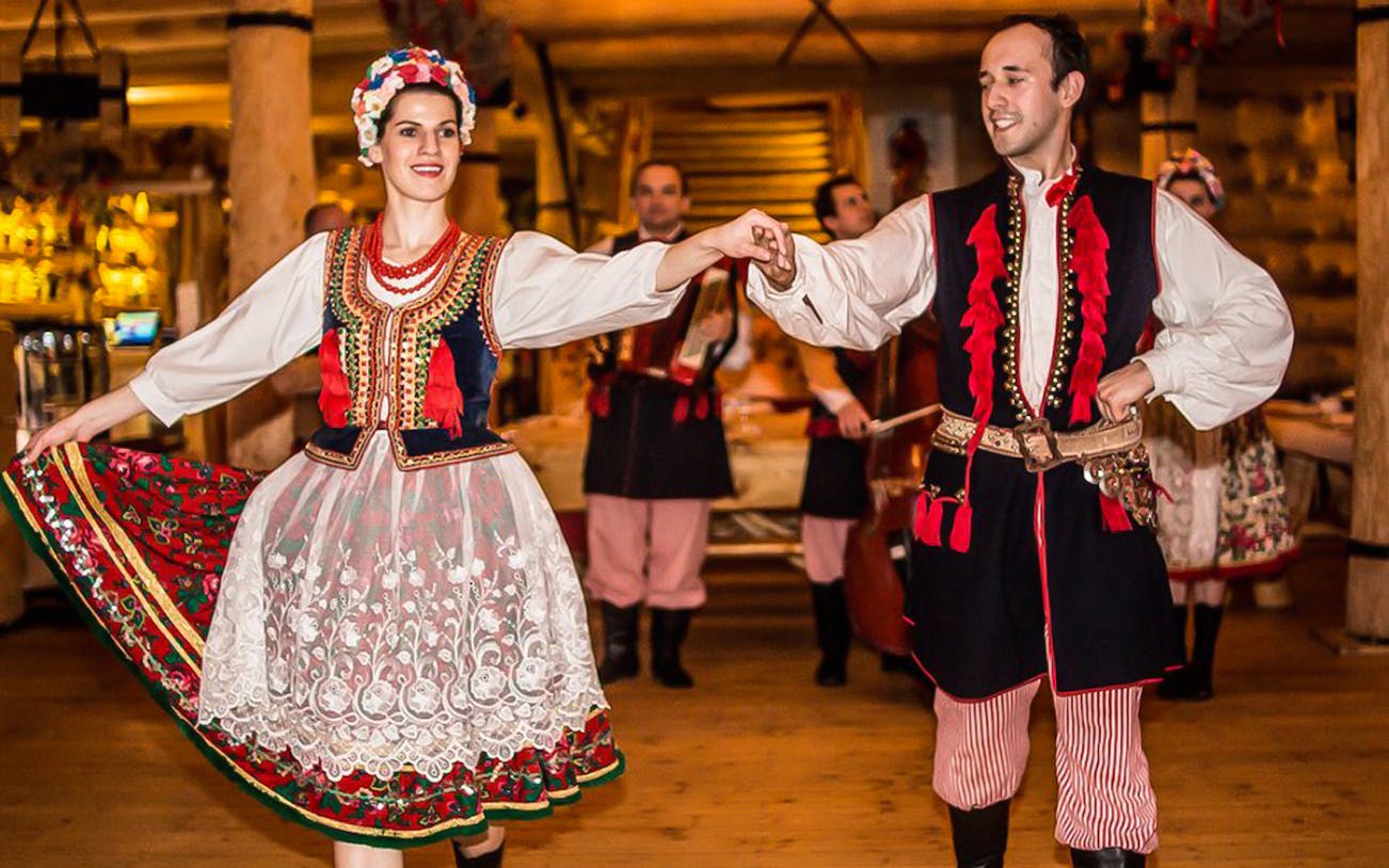 Dancers in traditional Polish costumes performing at a folk show with dinner.