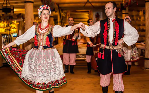 Dancers in traditional Polish costumes performing at a folk show with dinner.