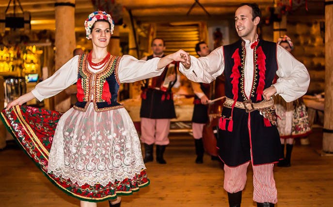 Dancers in traditional Polish costumes performing at a folk show with dinner.