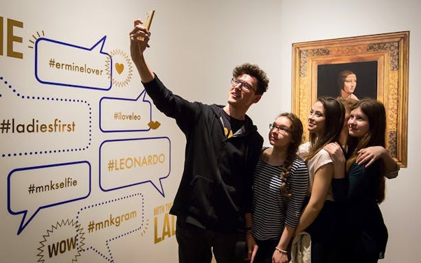 Visitors taking a selfie at Czartoryski Museum with "Lady with an Ermine" painting in the background.