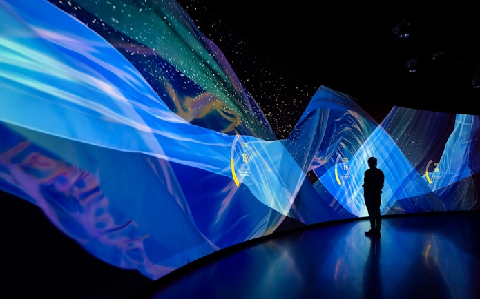 Silhouette of a person viewing digital art display at Torre Glories Lookout, Barcelona.