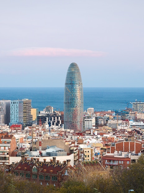 Torre Glòries in Barcelona skyline with Mediterranean Sea in the background.
