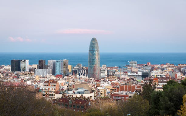 Torre Glòries in Barcelona skyline with Mediterranean Sea in the background.