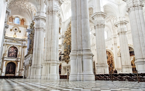 Interior of the Cathedral and Royal Chapel in Granada, featuring ornate columns and detailed artwork.