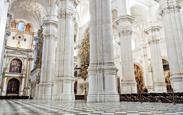 Interior of the Cathedral and Royal Chapel in Granada, featuring ornate columns and detailed artwork.