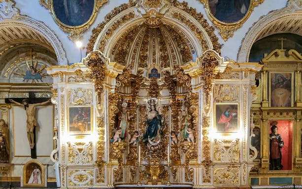 Ornate altar inside Cathedral and Royal Chapel, Granada, featuring religious statues and gold detailing.