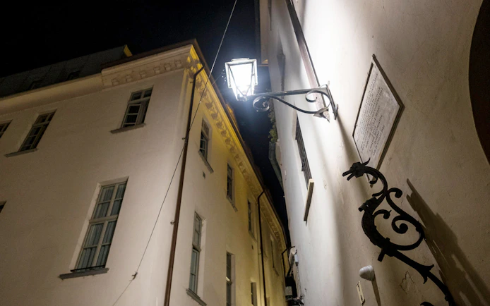 Night view of a narrow alley in Torino with historic buildings and a street lamp.