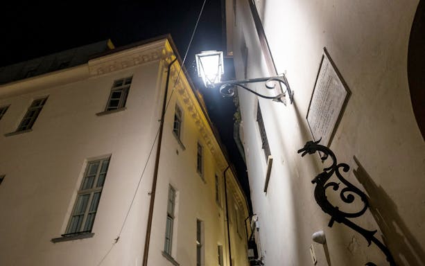Night view of a narrow alley in Torino with historic buildings and a street lamp.