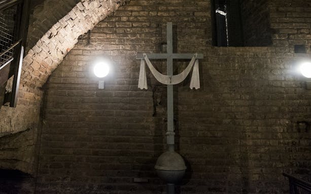 Cross in dimly lit brick cellar on Italian Guided Tour through Torino Noir.