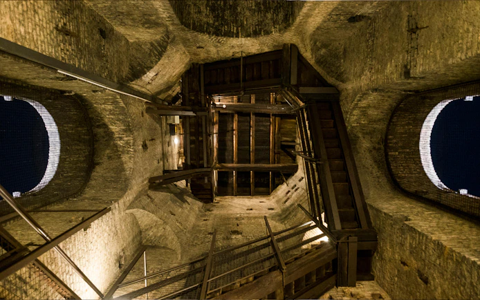 Interior view of a historic tower in Torino, featuring wooden stairs and brick walls.