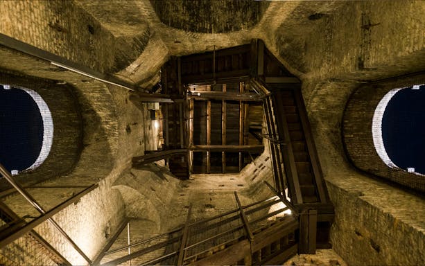 Interior view of a historic tower in Torino, featuring wooden stairs and brick walls.