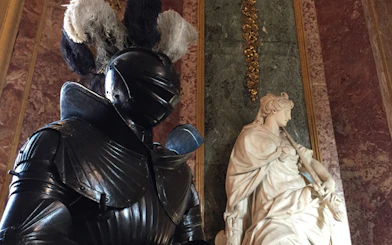 Knight armor and marble statue inside the Royal Palace of Turin.