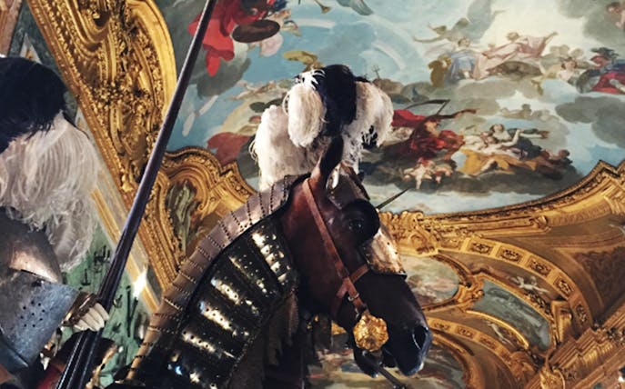 Armored horse and knight in the Royal Palace of Turin with ornate ceiling fresco.