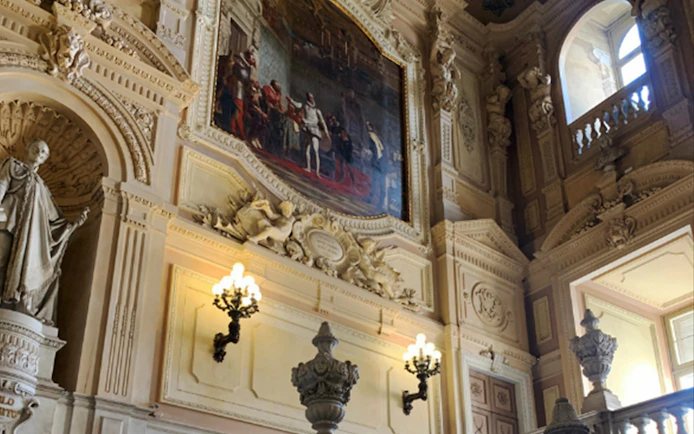 Interior of the Royal Palace of Turin with ornate sculptures and historical paintings.