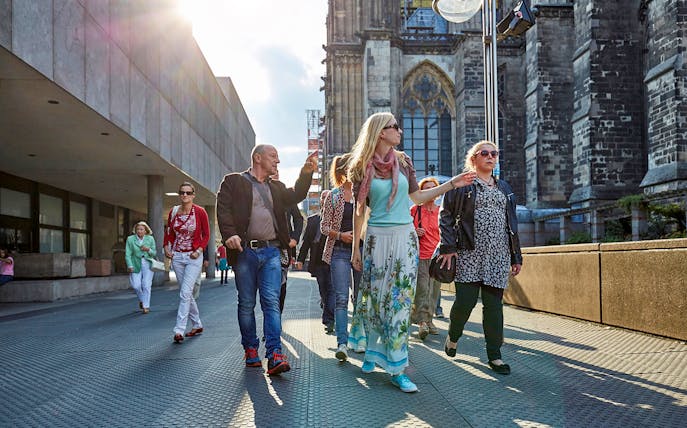 Group touring Cologne Cathedral exterior with guide.