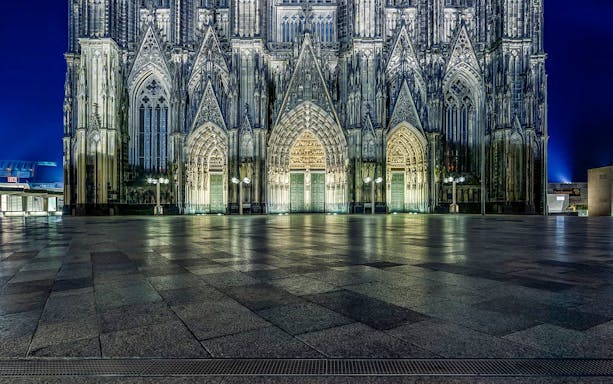 Cologne Cathedral exterior illuminated at night during guided tour.