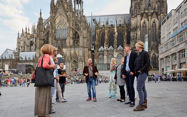 Tour group in front of Cologne Cathedral, exploring city stories and local culture.
