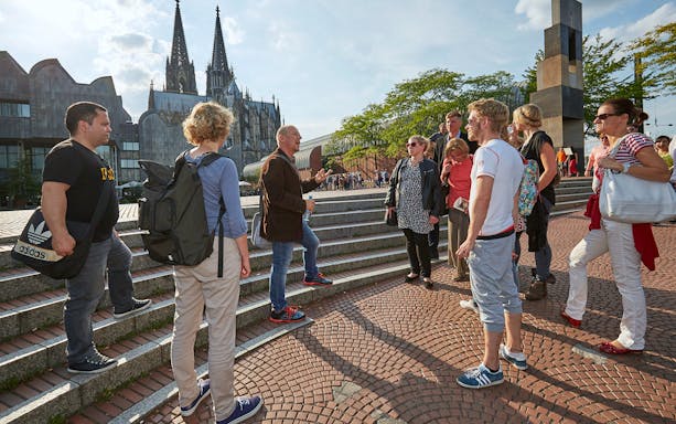 Tour group listening to a guide near Cologne Cathedral, Germany.