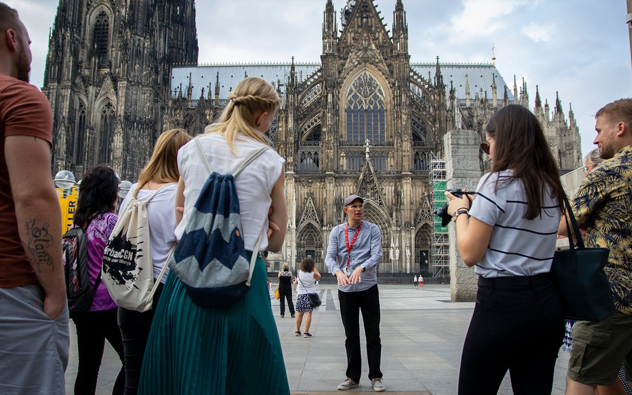 Tour group listening to a guide in front of Cologne Cathedral, Germany.