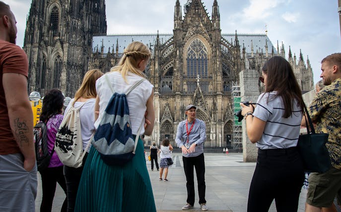 Tour group listening to a guide in front of Cologne Cathedral, Germany.