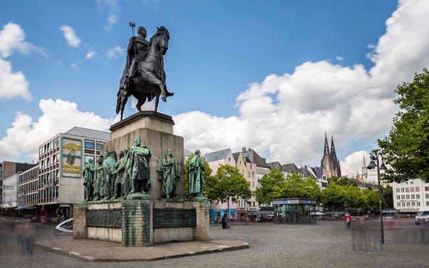 Equestrian statue in Cologne's Old Town with Cologne Cathedral in the background.