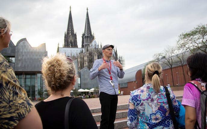 Tour guide leading a group near Cologne Cathedral in Germany.