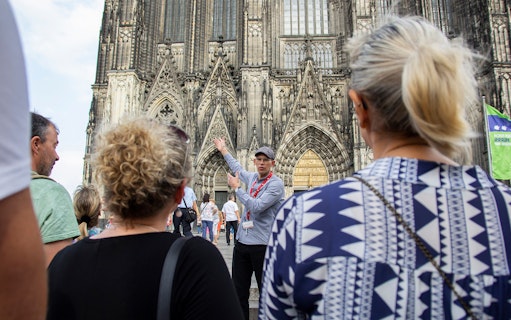 Tour guide leading a group in front of Cologne Cathedral, Germany.