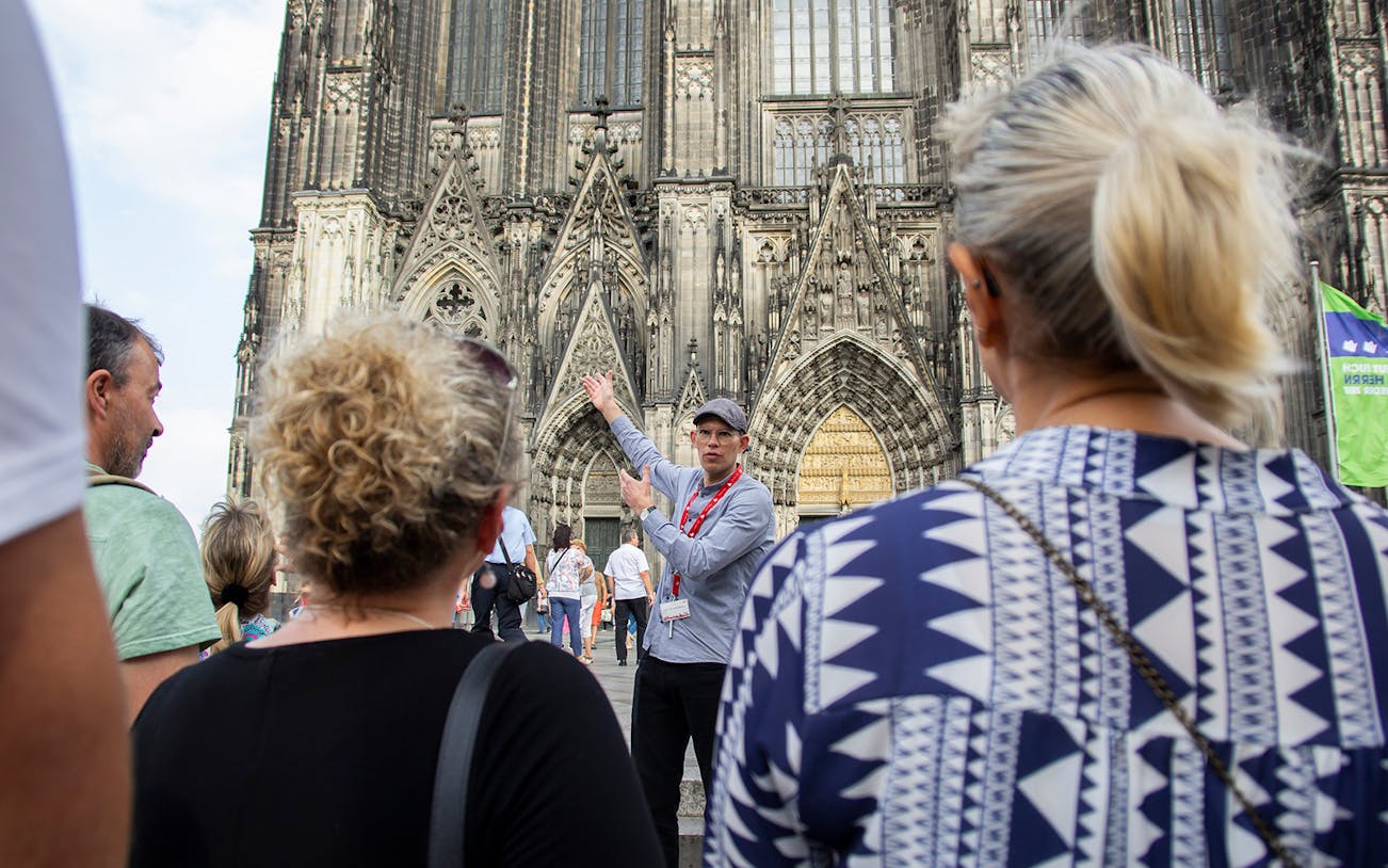 Tour guide leading a group in front of Cologne Cathedral, Germany.