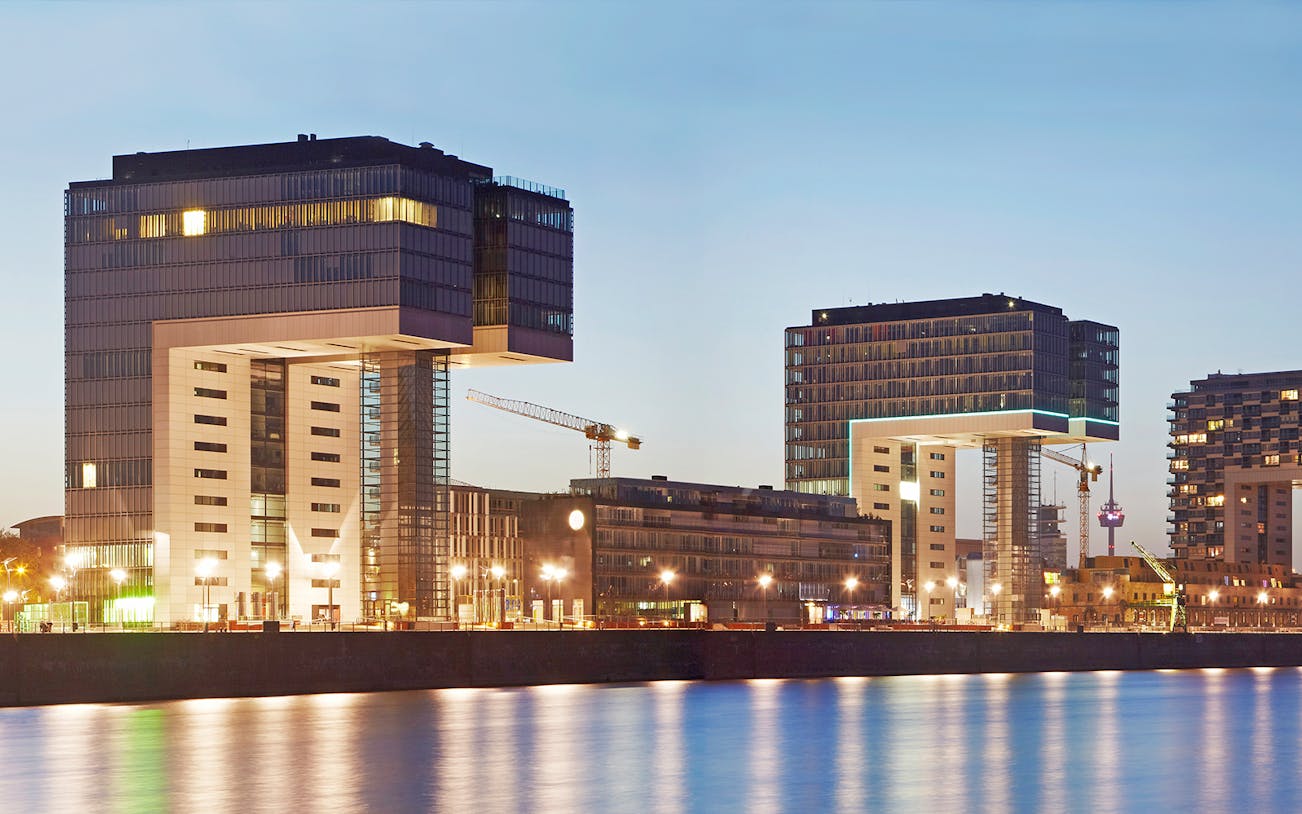 Kranhäuser buildings along the Rhine River in Cologne at dusk.