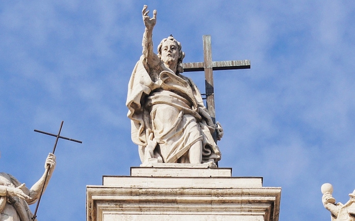Statue atop St. John Lateran Basilica in Rome holding a cross.