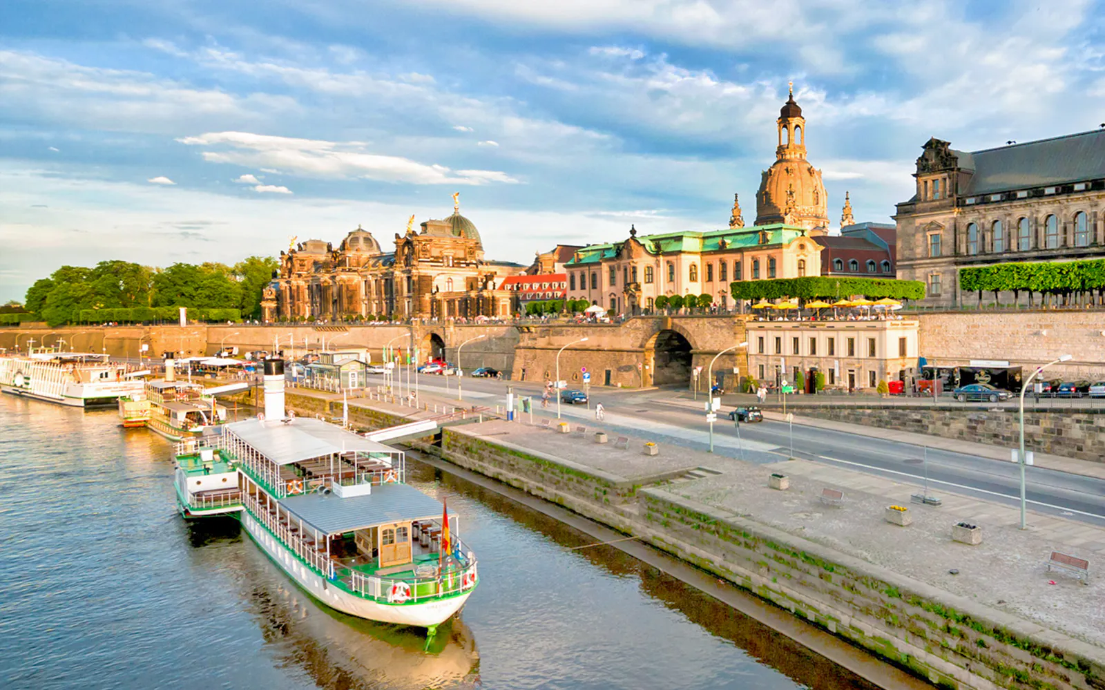Dresden riverside with historic buildings and a tour boat docked along the Elbe River.