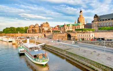 Dresden riverside with historic buildings and a tour boat docked along the Elbe River.