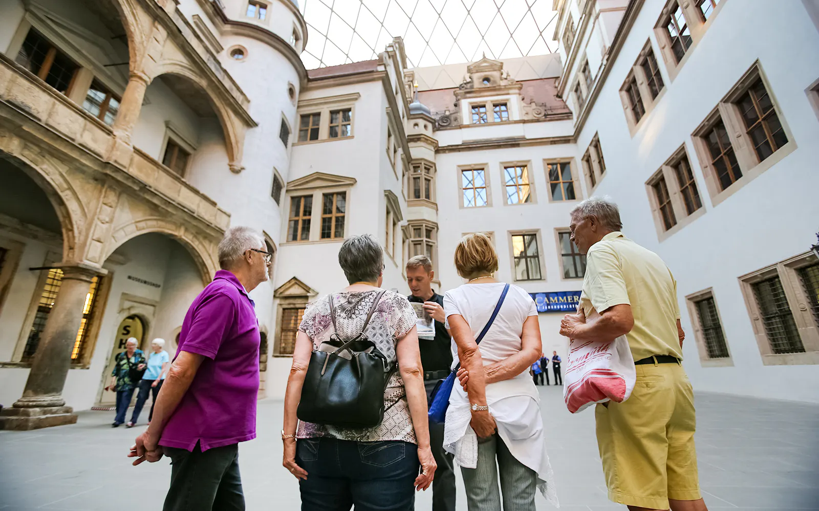 Tour group listening to a guide in a historic courtyard in Dresden, Germany.