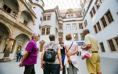 Tour group listening to a guide in a historic courtyard in Dresden, Germany.