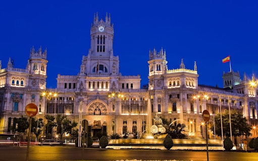 Illuminated Palacio de Cibeles in Madrid at dusk during sunset tour.