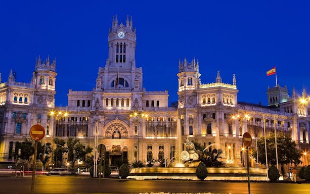 Illuminated Palacio de Cibeles in Madrid at dusk during sunset tour.